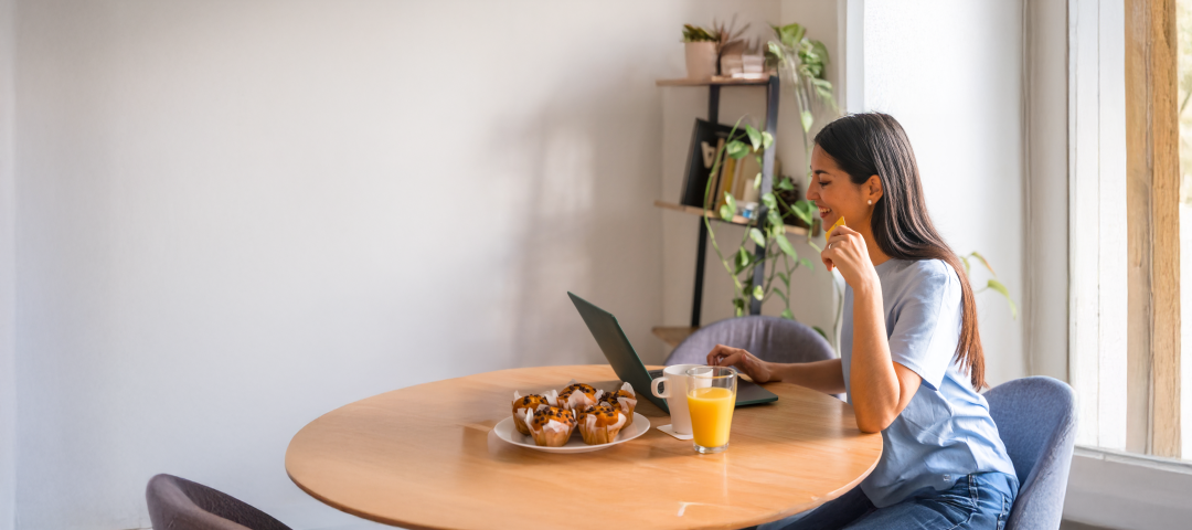 Woman eating breakfast with laptop