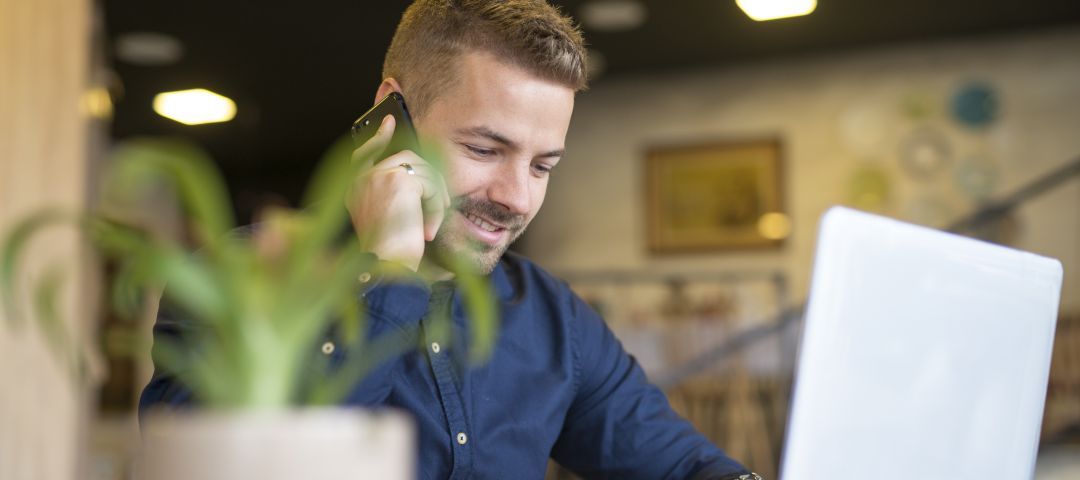 Young Man talking on Phone with Laptop