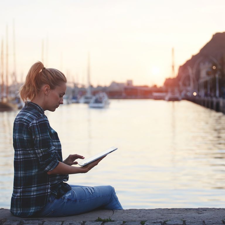 Woman using Ipad at the lake