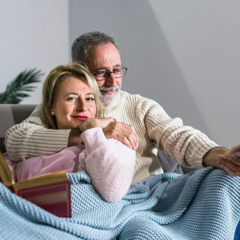 WTC Communications Perth - Senior couple comfortably relaxing on their couch at home, watching WTC TV with a remote.